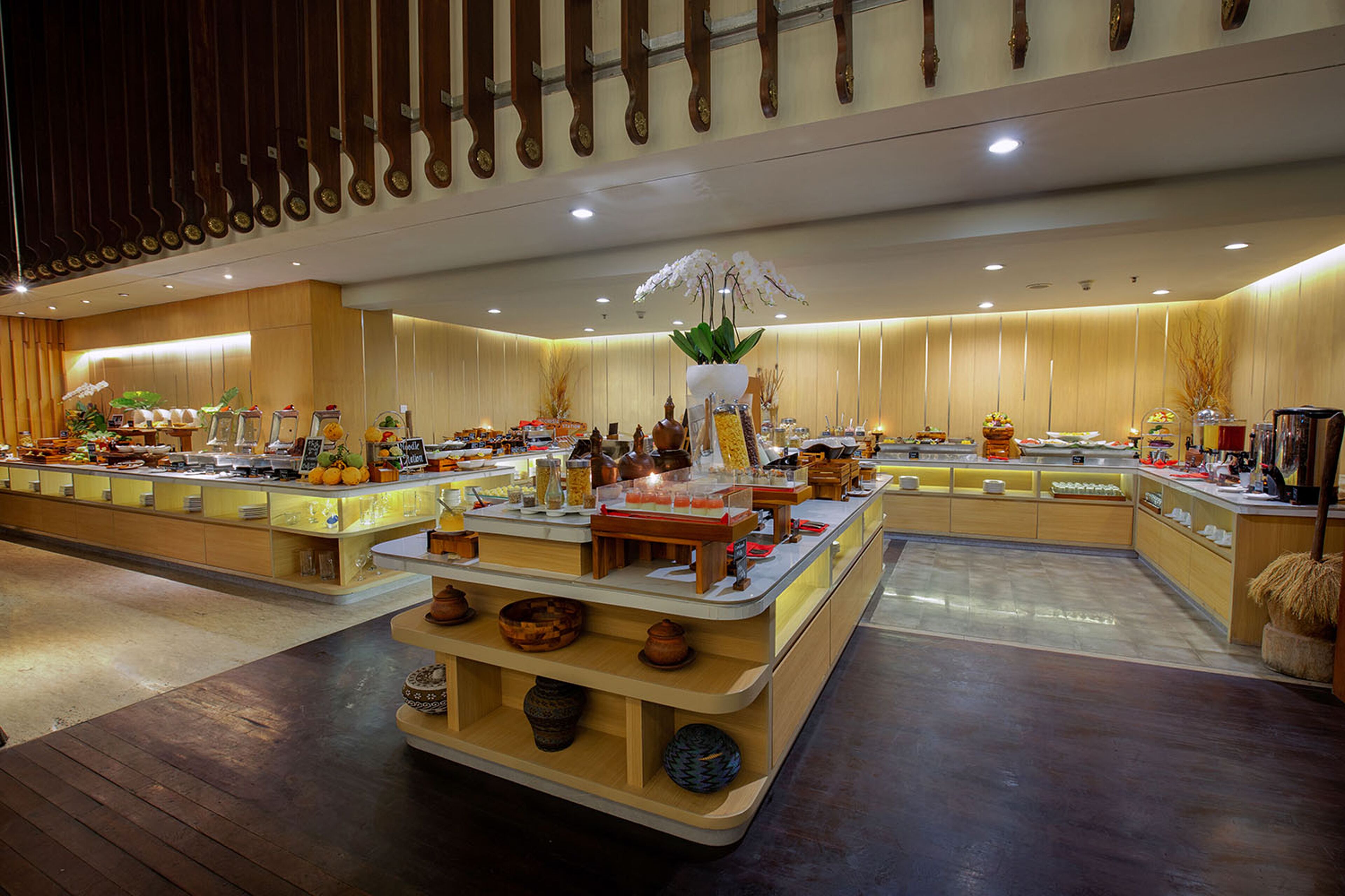 A spacious hotel lobby with a central reception desk, multiple seating areas, and a variety of decorative items including plants and pottery.