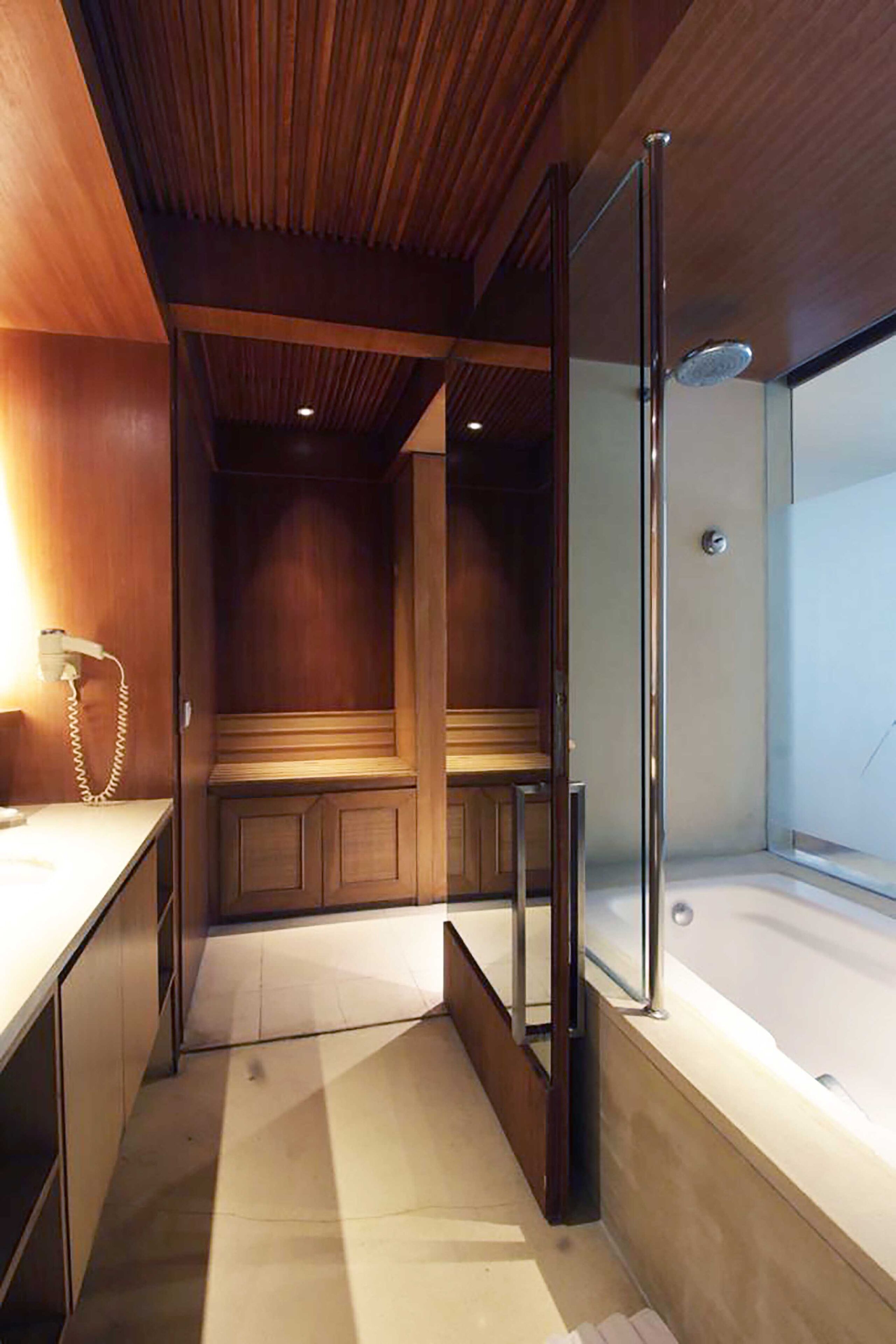 Un bagno moderno con soffitto in legno, cabina doccia in vetro e panca integrata.