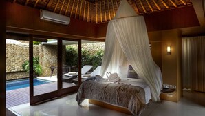 A bedroom with a canopy bed, a stone wall, a pool, and a view of the outdoors. - THE HAVEN Bali Seminyak (Seminyak)