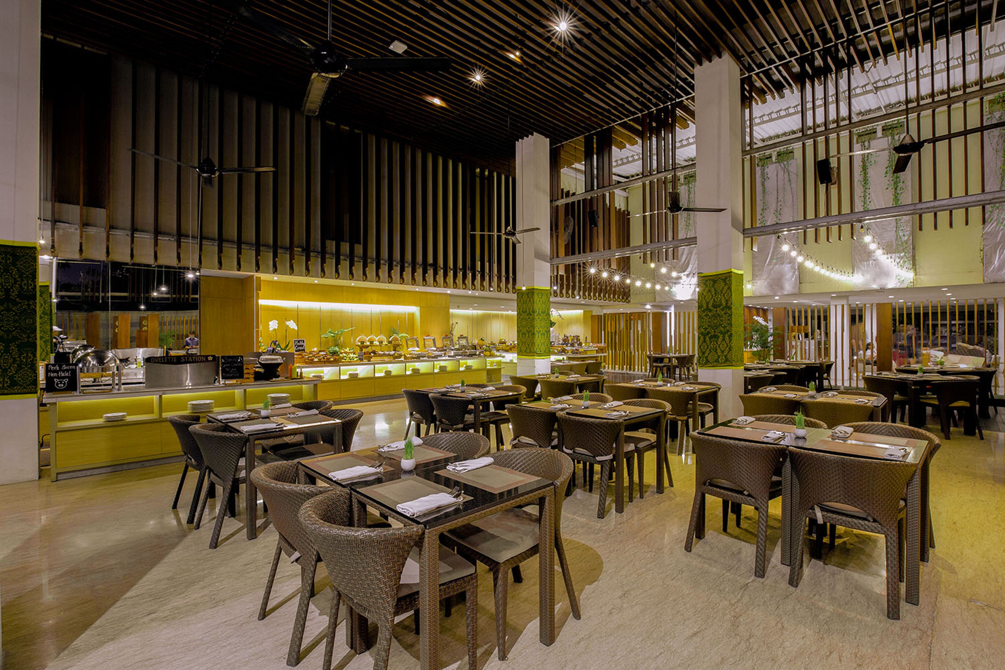 A modern restaurant with high ceilings, a central bar area, and multiple dining tables and chairs.