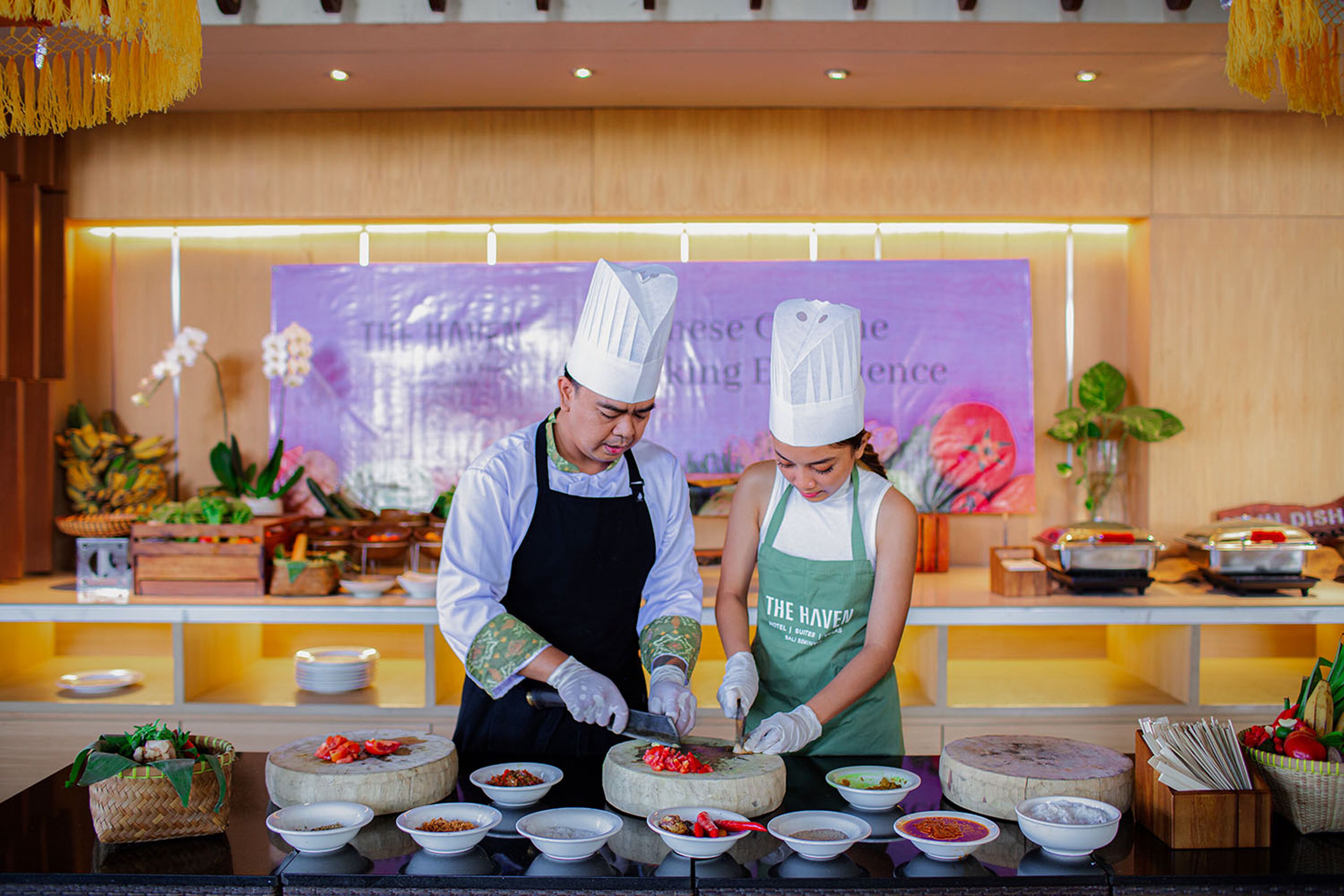 Ein Koch und ein Servicekraft bereiten Speisen an einem Buffet zu, im Hintergrund ist ein Banner sichtbar.