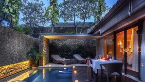 An outdoor pool area with lounge chairs, a table set for dining, and candles. - THE HAVEN Bali Seminyak (Seminyak)