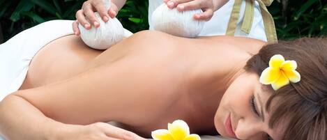 A person receiving a massage with a flower in their hair.