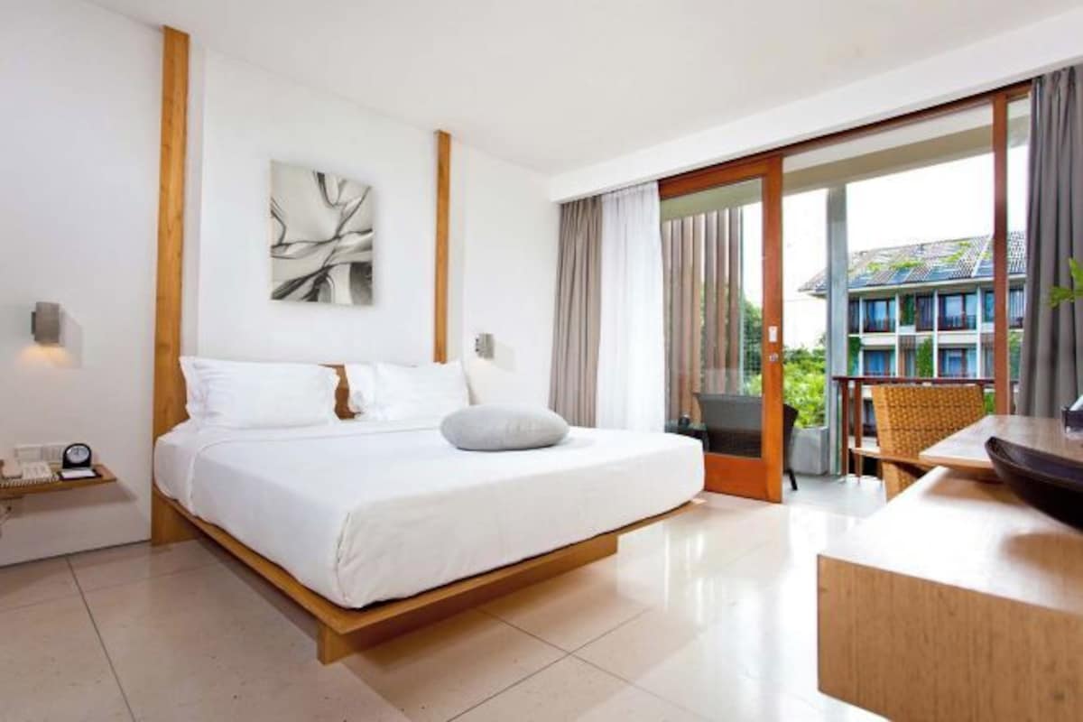 Una habitación de hotel moderna con una cama grande, un escritorio y un balcón con vistas.