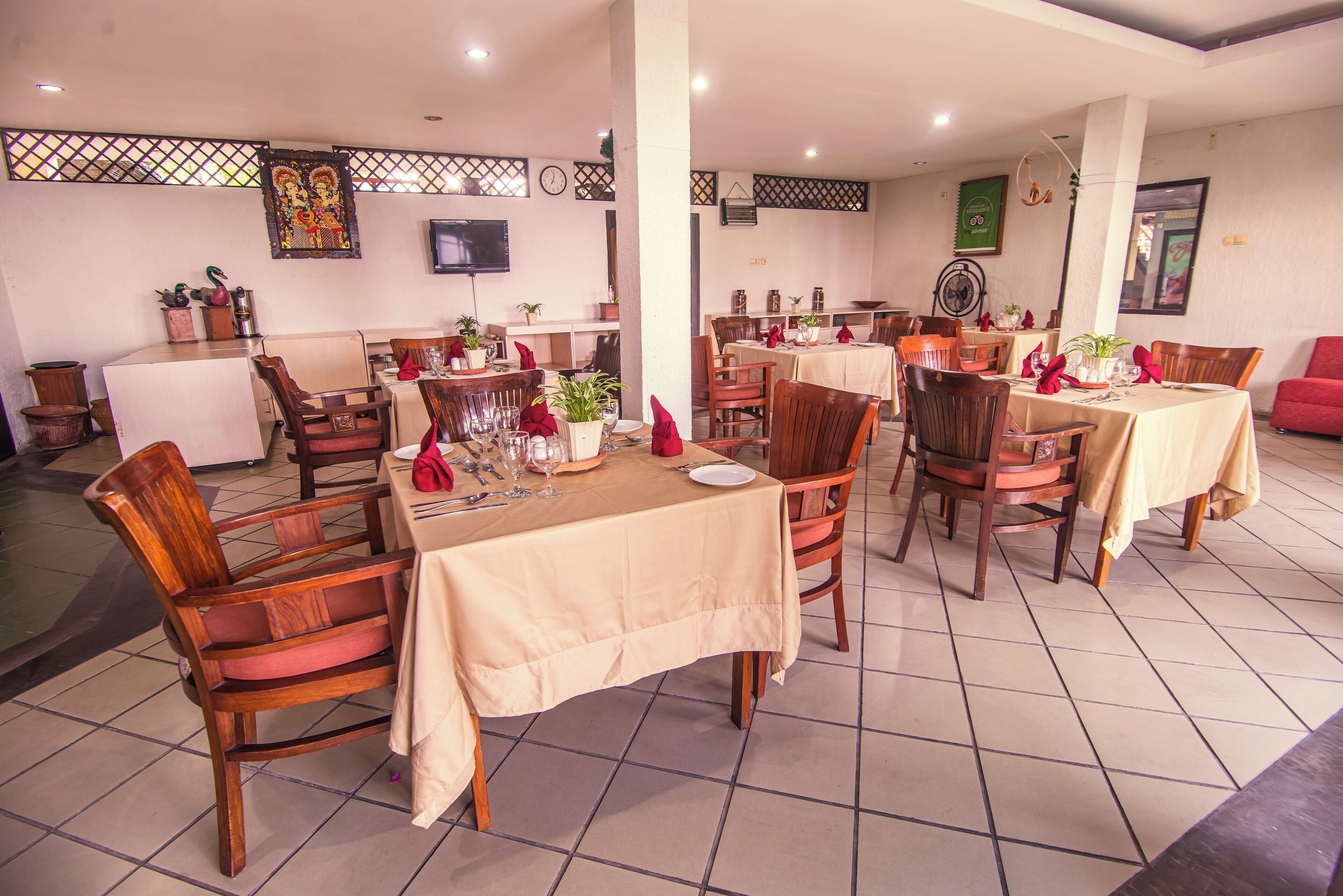 A restaurant with multiple tables and chairs, a counter, and decorative elements like plants and artwork on the walls.