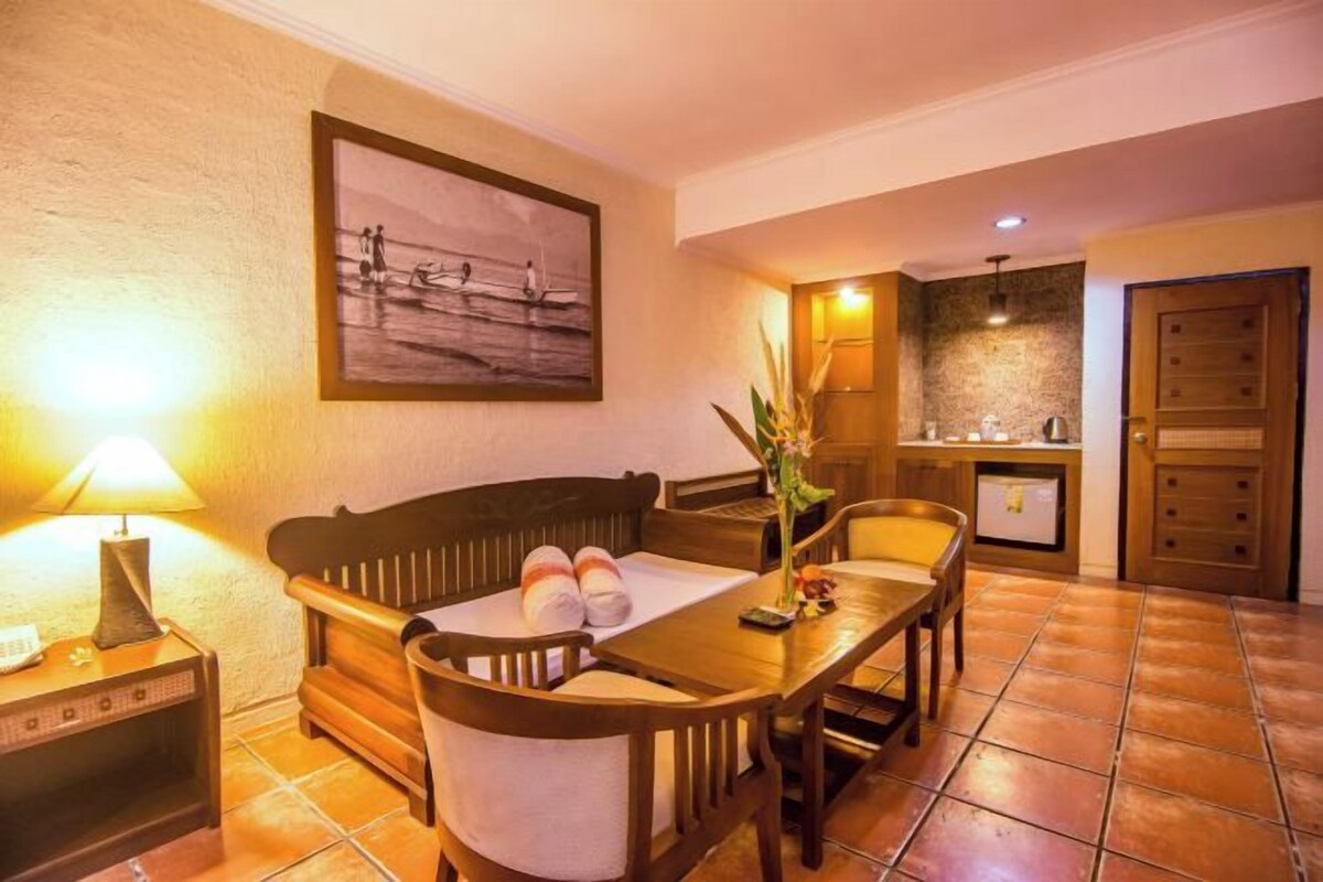 A cozy room with a wooden sofa, a dining table, and a kitchen area.