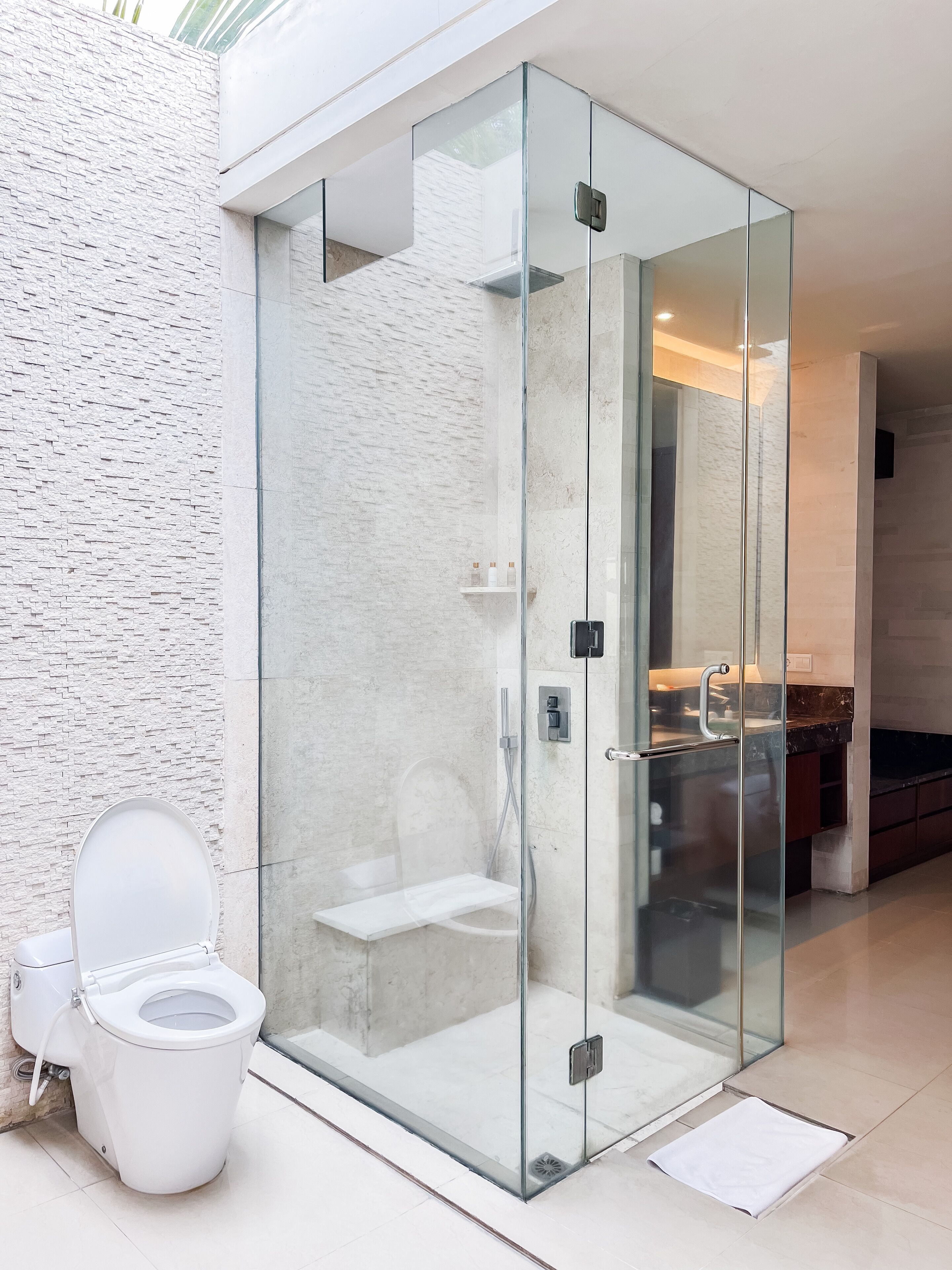 A modern bathroom with a glass-enclosed shower, a toilet, and a marble countertop.