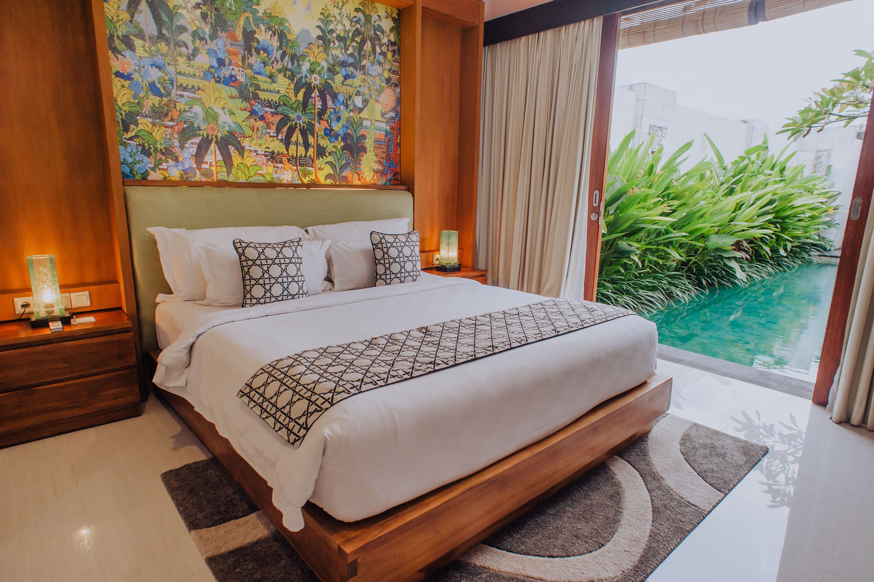 Un dormitorio amplio con una cama grande, una mesita de noche y vistas a una piscina.