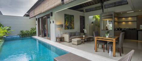 Una casa moderna con piscina, mobiliario de exterior y zona de cocina.