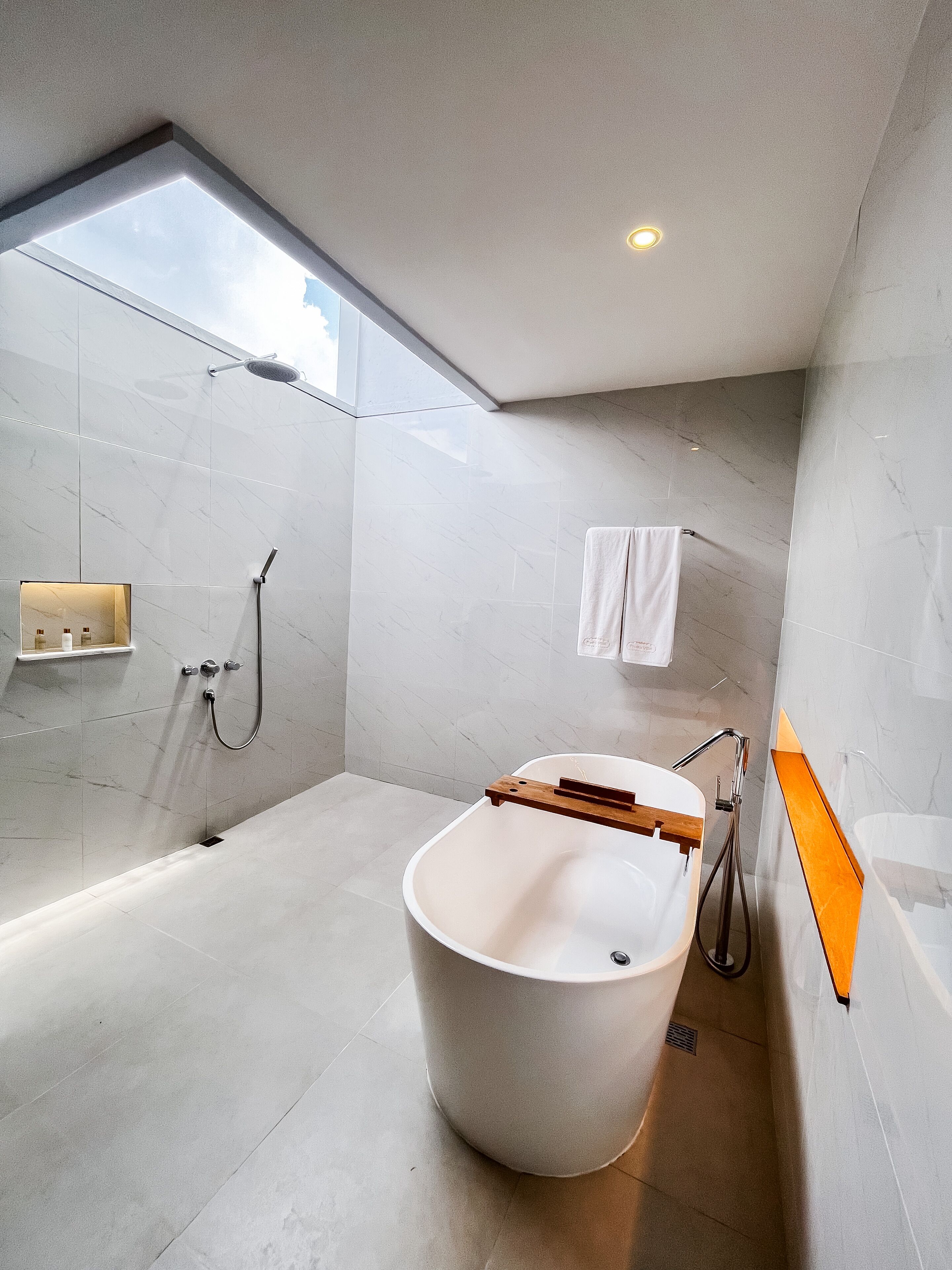 Un baño moderno con tragaluz, una bañera independiente y zona de ducha.