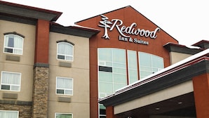 A Redwood Inn & Suites building with a stone facade and large windows. - Redwood Inn & Suites - Grande Prairie (Clairmont)
