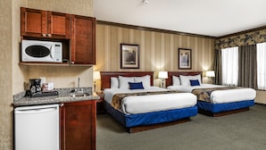 A hotel room with two beds, a microwave, a small kitchenette, and a large window with curtains. - Redwood Inn & Suites - Grande Prairie (Clairmont)