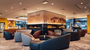 Zona de bar lounge con asientos y chimenea.