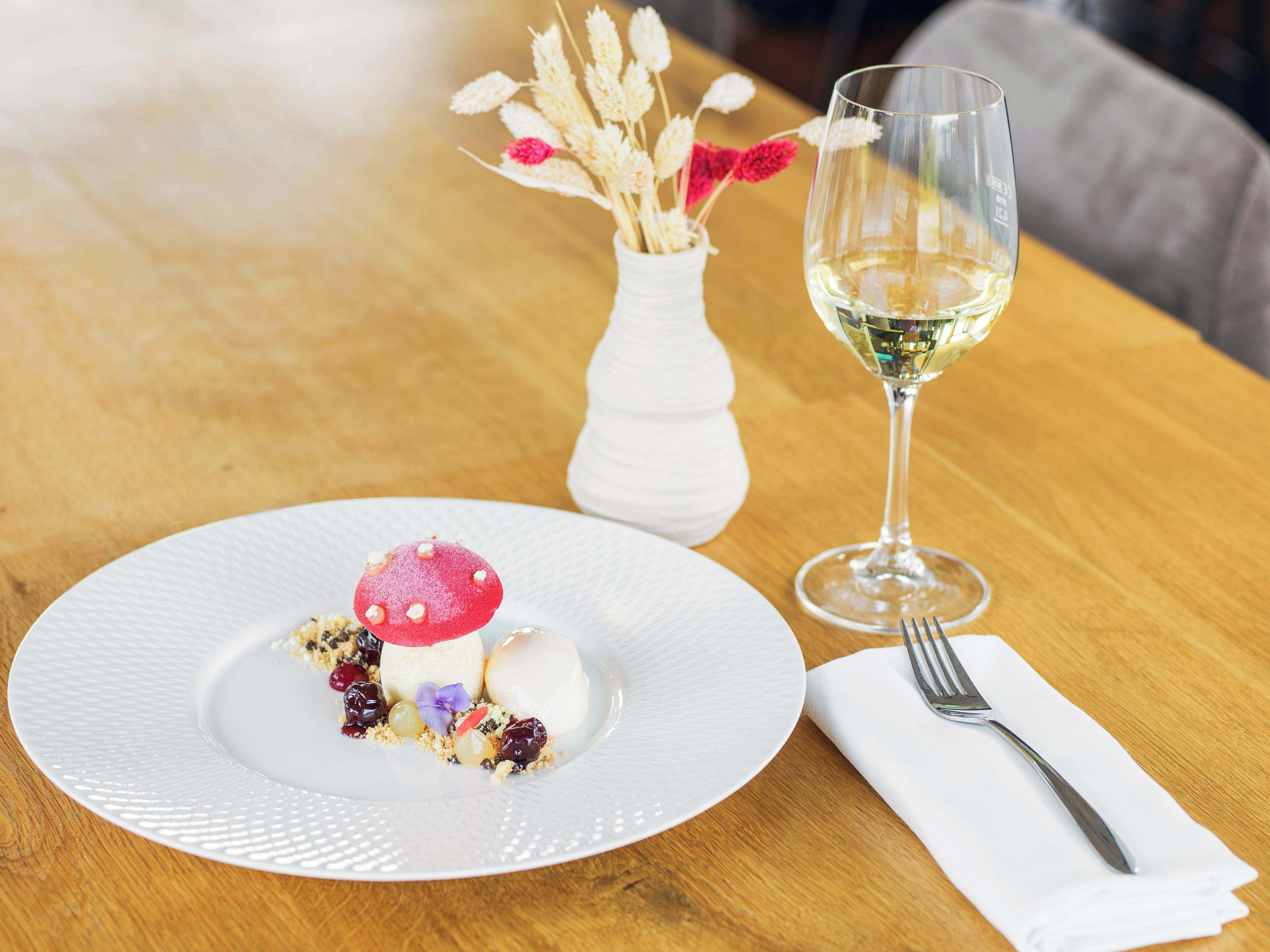 A dessert plate with a variety of sweets and a glass of white wine on a wooden table.