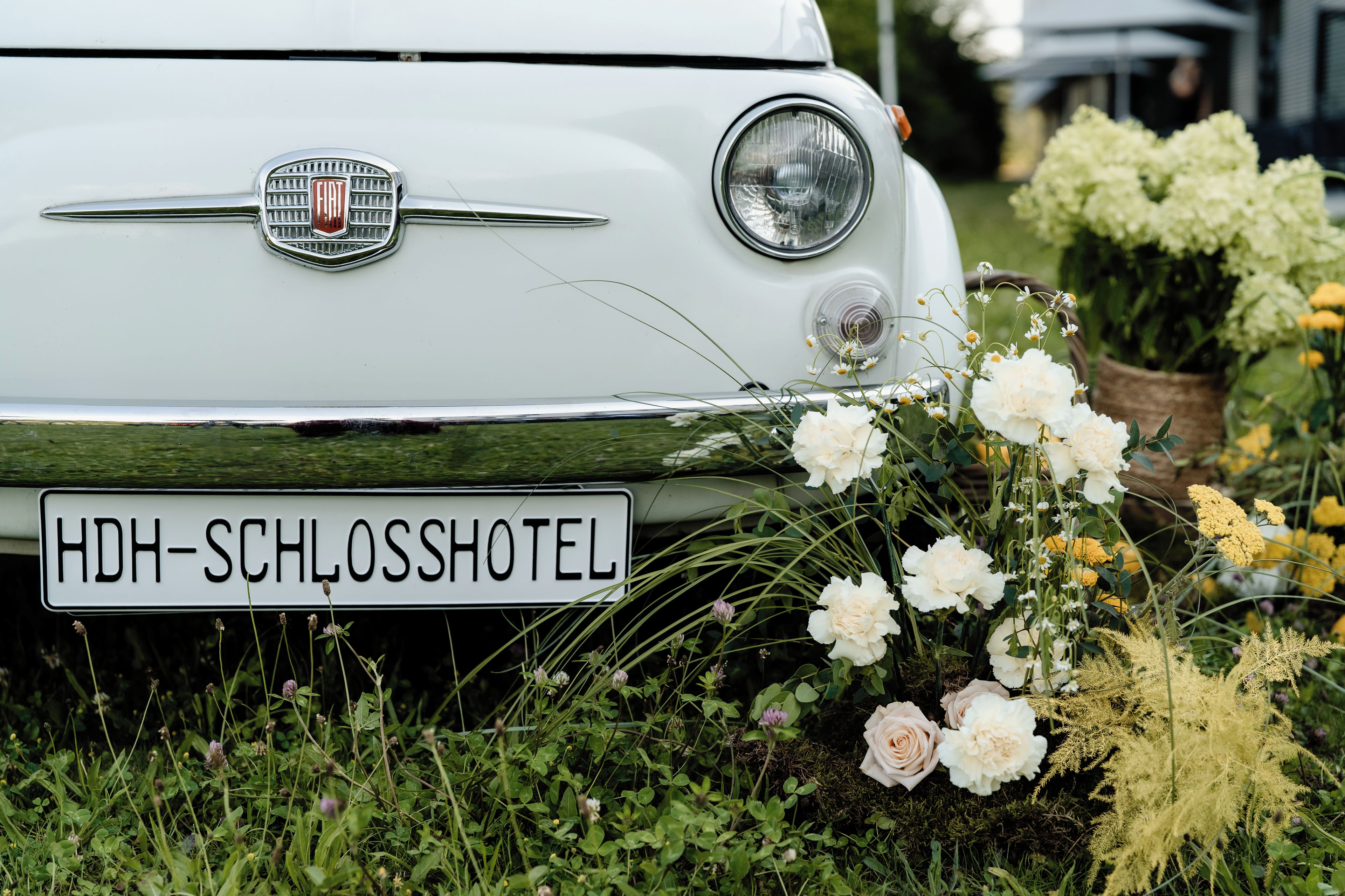 Un coche Fiat clásico con una matrícula que dice 'HDH-SCHLOSSHOTEL'.