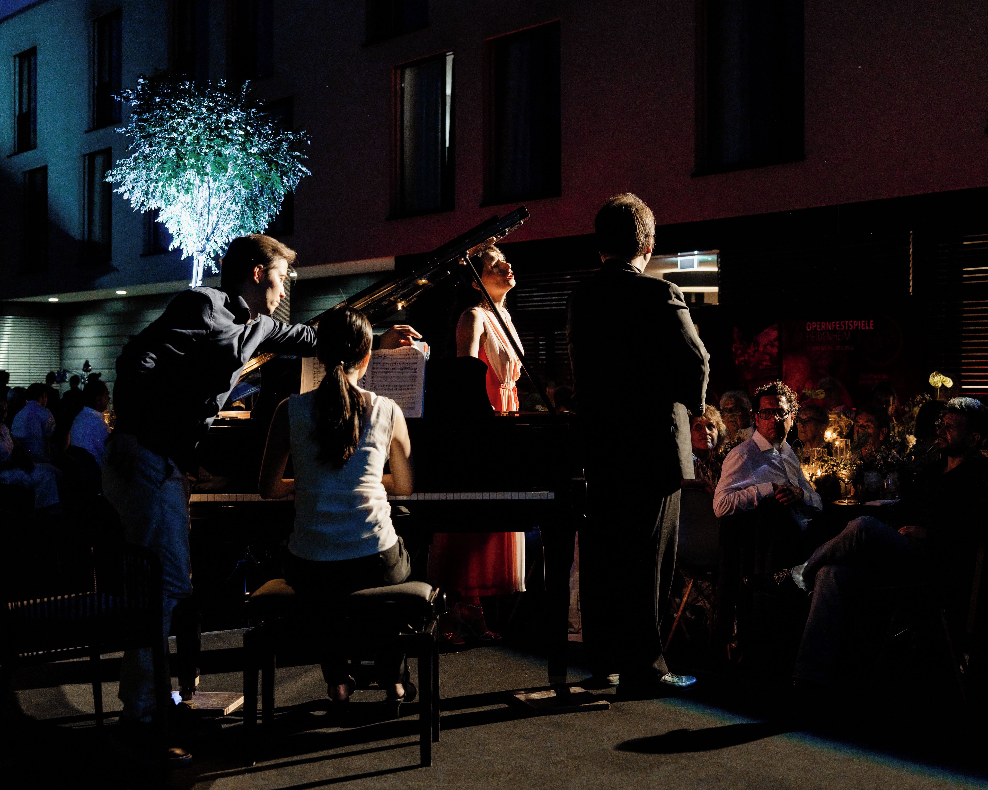 An outdoor event with a piano and a crowd of people.