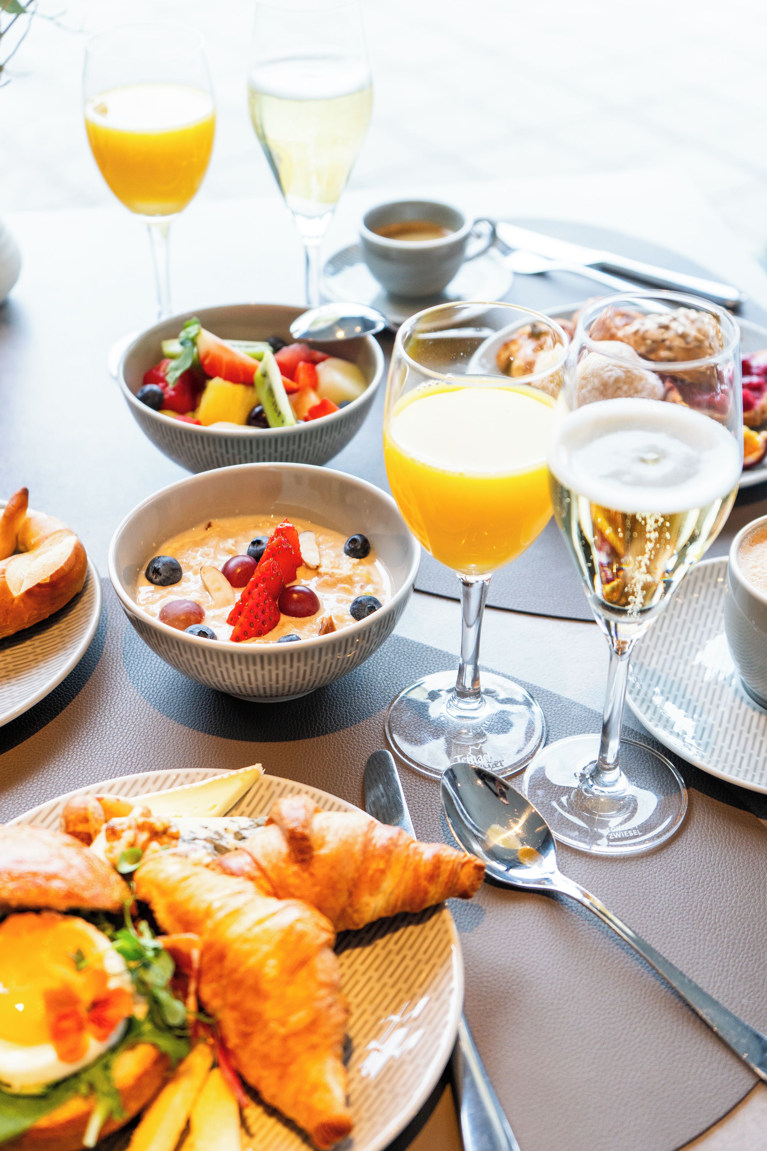 Desayuno con diversos platos, incluyendo cruasanes, fruta y bebidas.