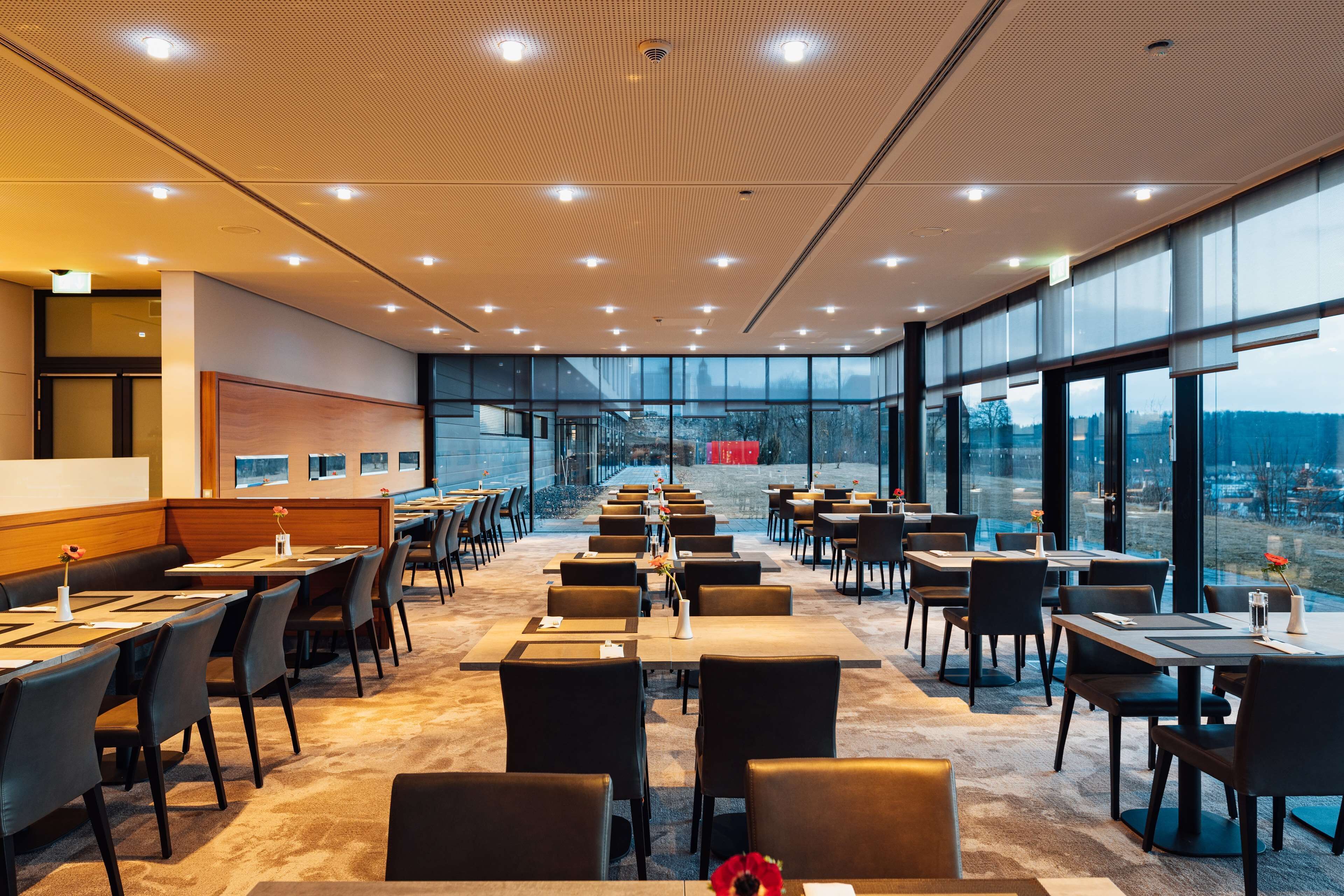 A modern dining area with tables and chairs, large windows, and a view of the cityscape.