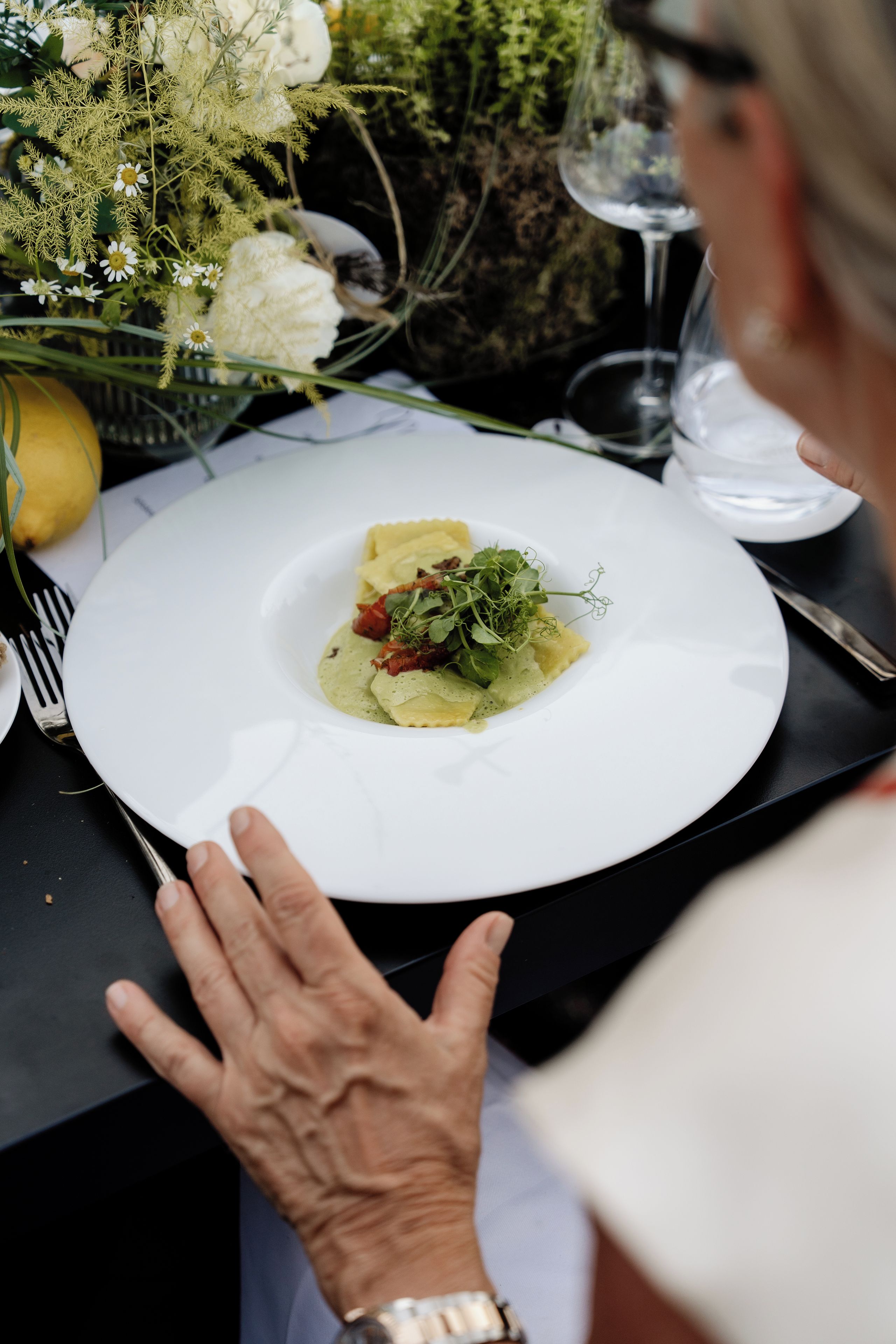 Una mesa de comedor con un plato blanco de comida, un tenedor y un vaso de agua.