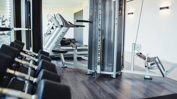 Une salle de sport équipée de machines de cardio, de matériel de musculation et d’un miroir.