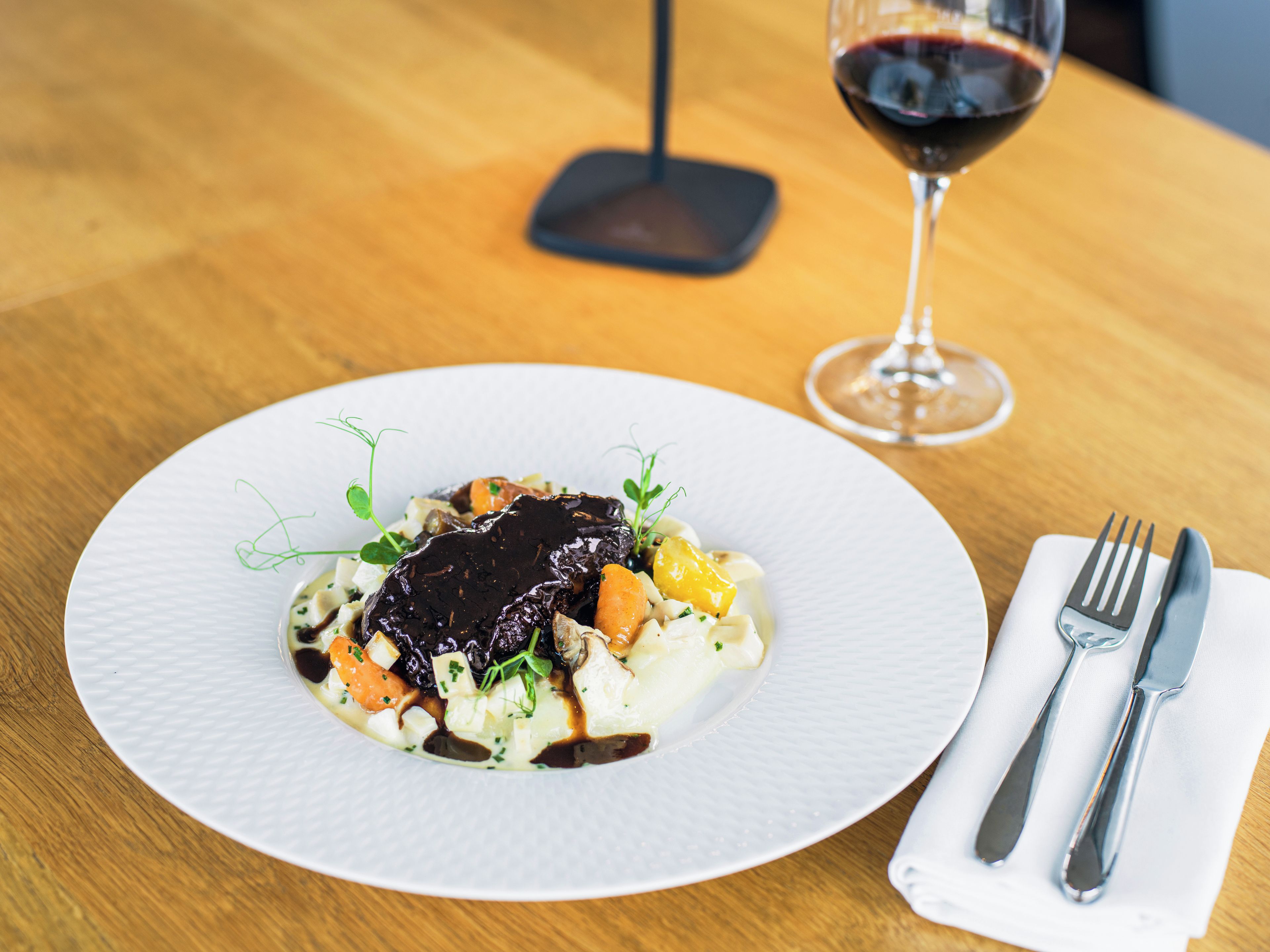 A plate of food with a glass of red wine on a wooden table.
