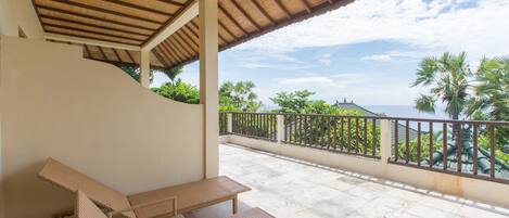 A covered outdoor seating area with wicker furniture and a view of palm trees and mountains.