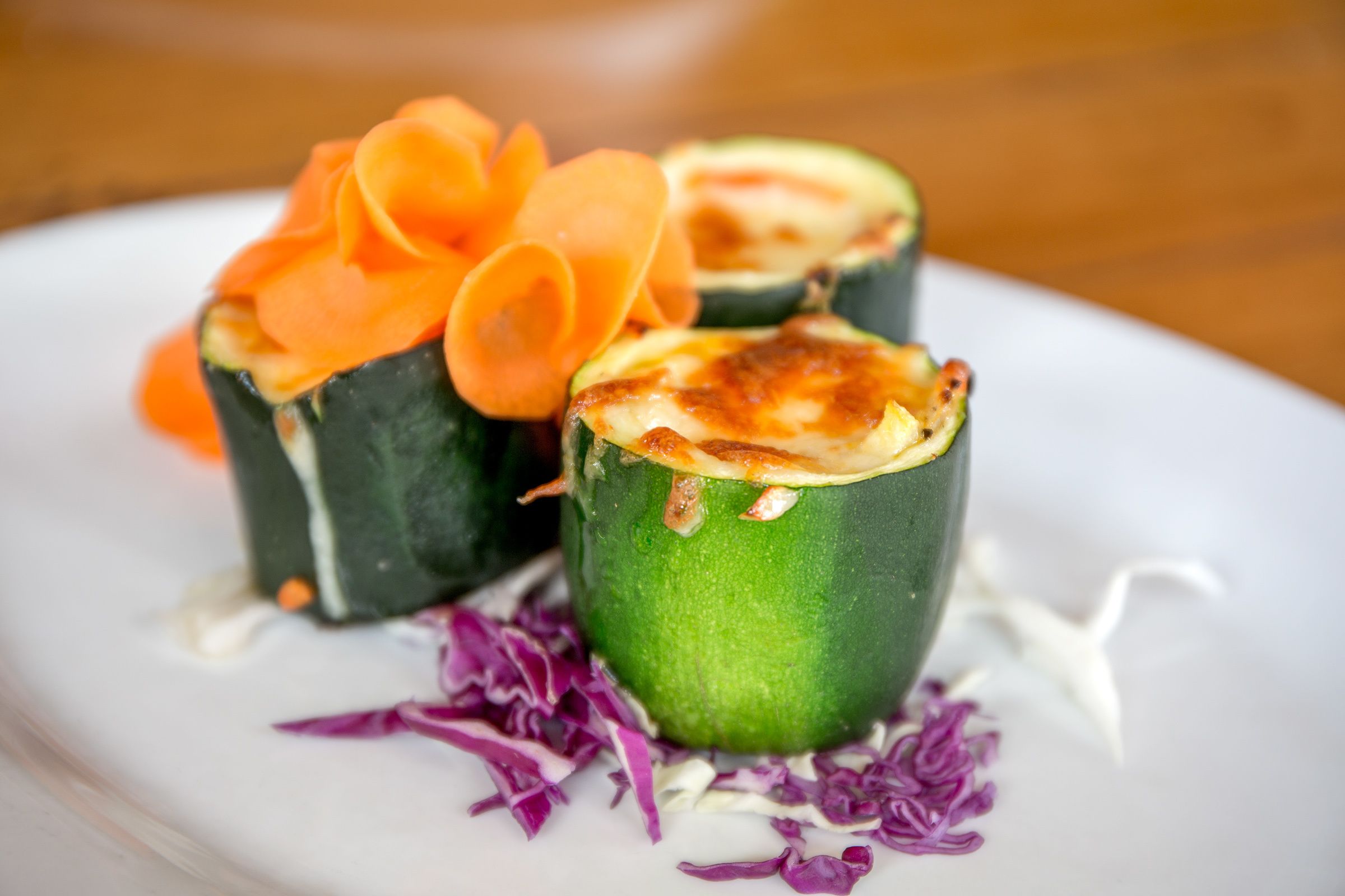 A plate with stuffed zucchini halves, garnished with carrot slices and purple cabbage.