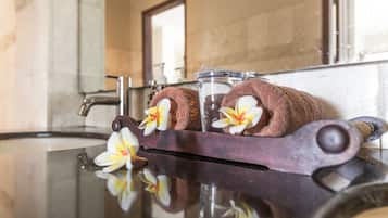 Un bagno con lavabo in marmo, portasciugamani con due asciugamani e un bicchiere d'acqua.