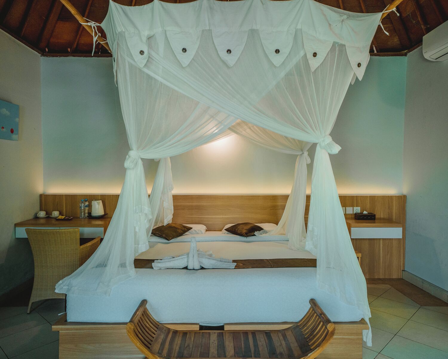 Un dormitorio con cama a dosel, mesitas de noche, una silla y cabecera de madera.