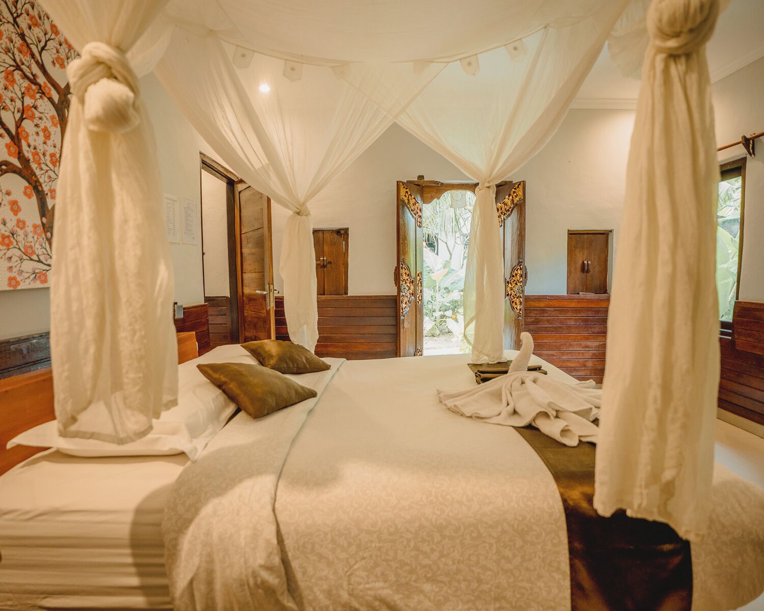 Un dormitorio amplio con una cama grande, dosel y vistas al exterior.