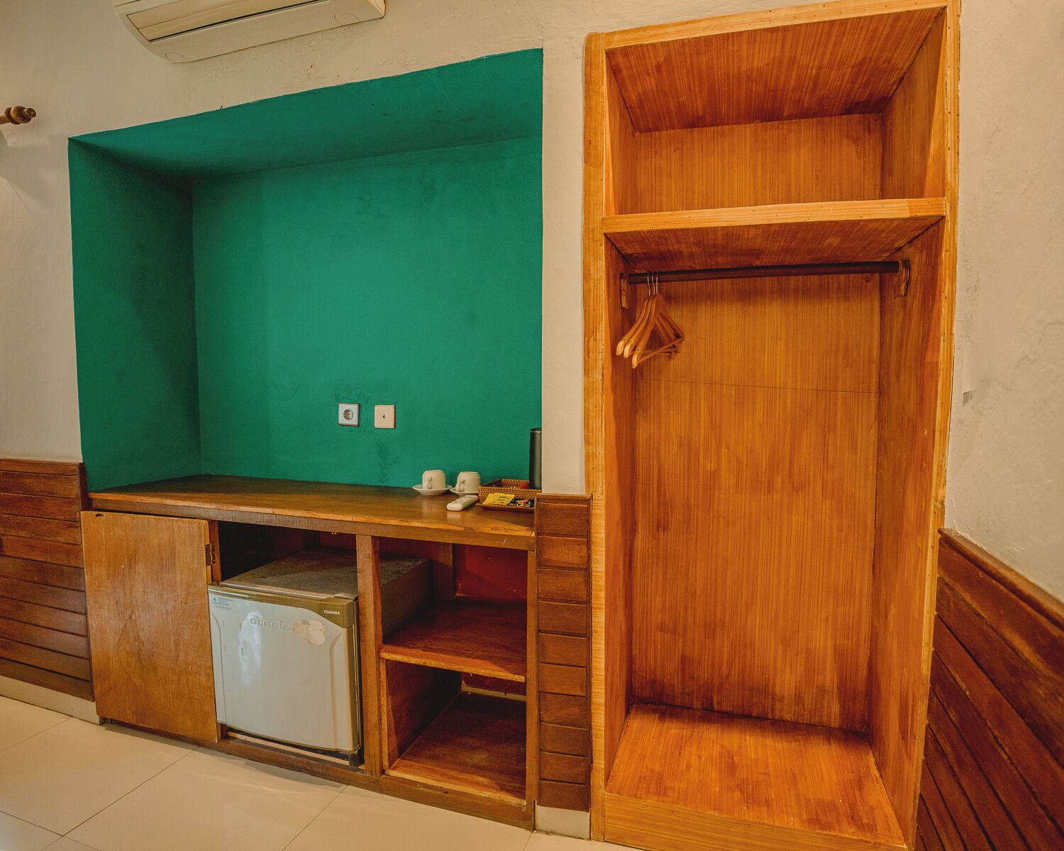 A room with a wooden cabinet, a green wall, and a wooden door.