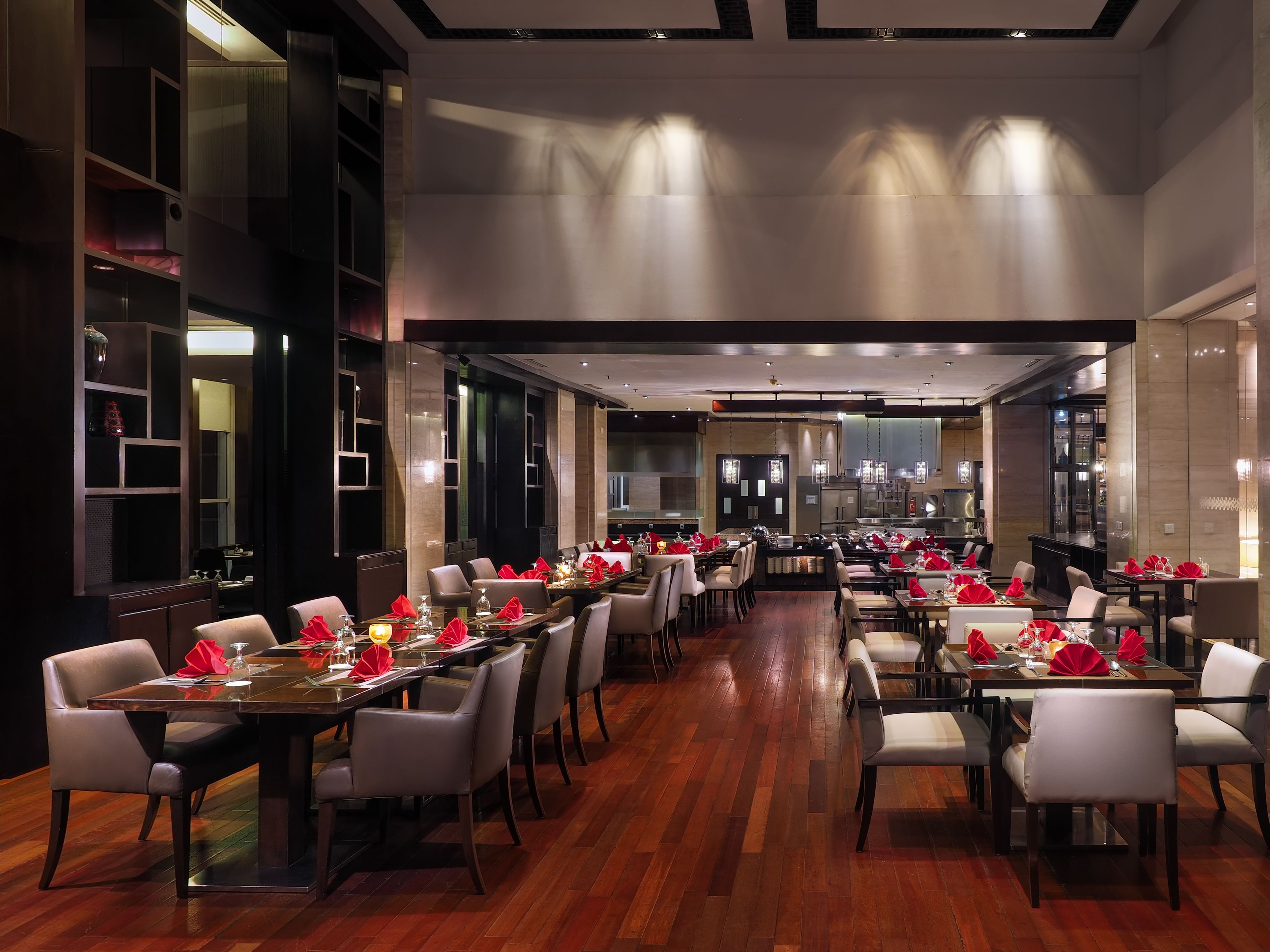 Un restaurant spacieux doté de nombreuses tables, chacune étant dressée avec des serviettes et des verres rouges.