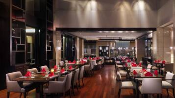 Un restaurant spacieux doté de nombreuses tables, chacune étant dressée avec des serviettes et des verres rouges.