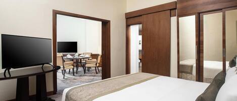 Una habitación de hotel con cama, televisión, mesa de comedor con sillas y espejo.