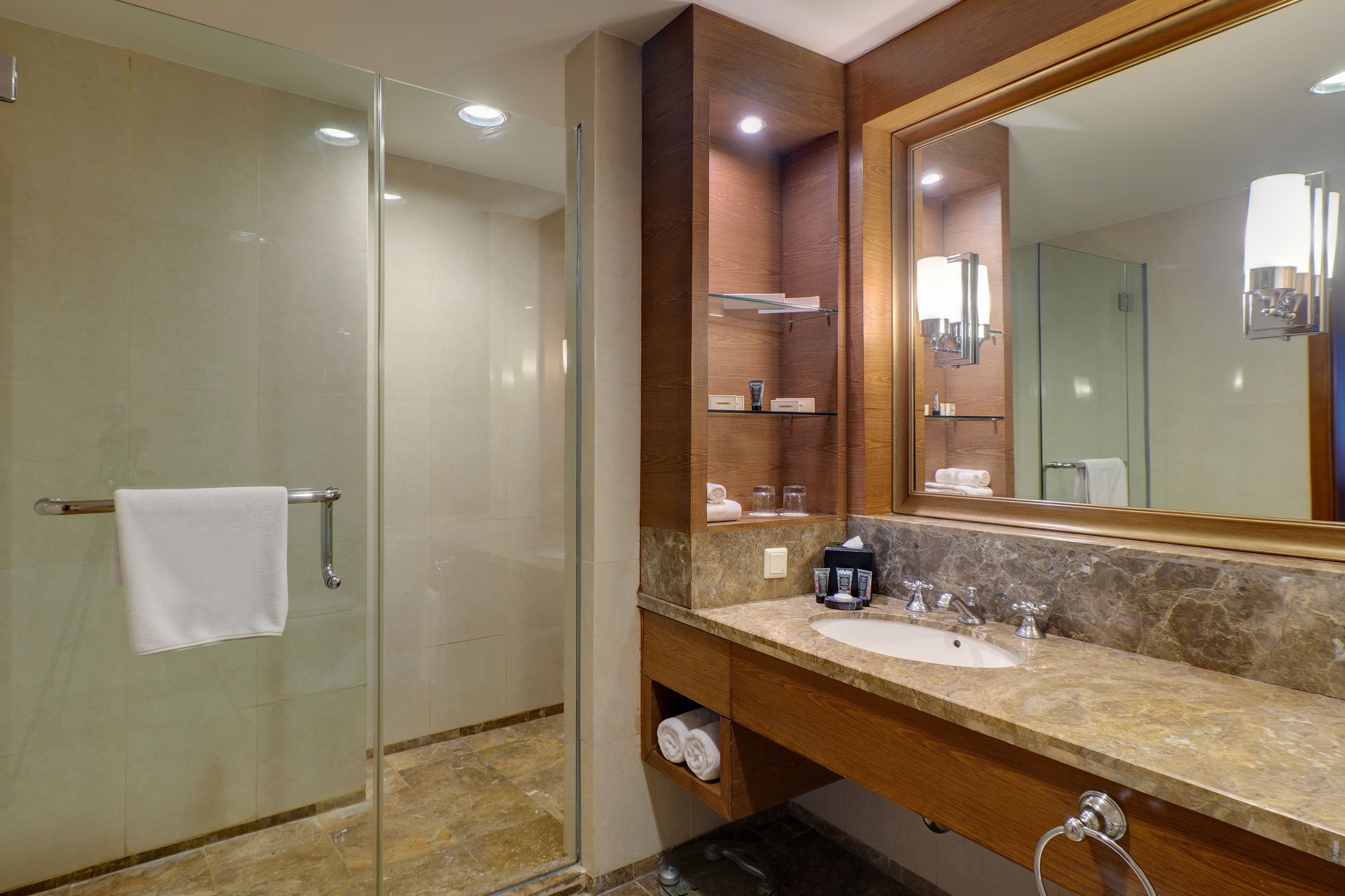 Un baño moderno con cabina de ducha de vidrio, lavabo de mármol y un espejo grande.