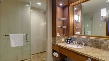 Un bagno moderno con doccia in vetro, lavabo in marmo e uno specchio grande.