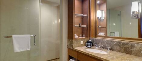 Un baño moderno con cabina de ducha de vidrio, lavabo de mármol y un espejo grande.