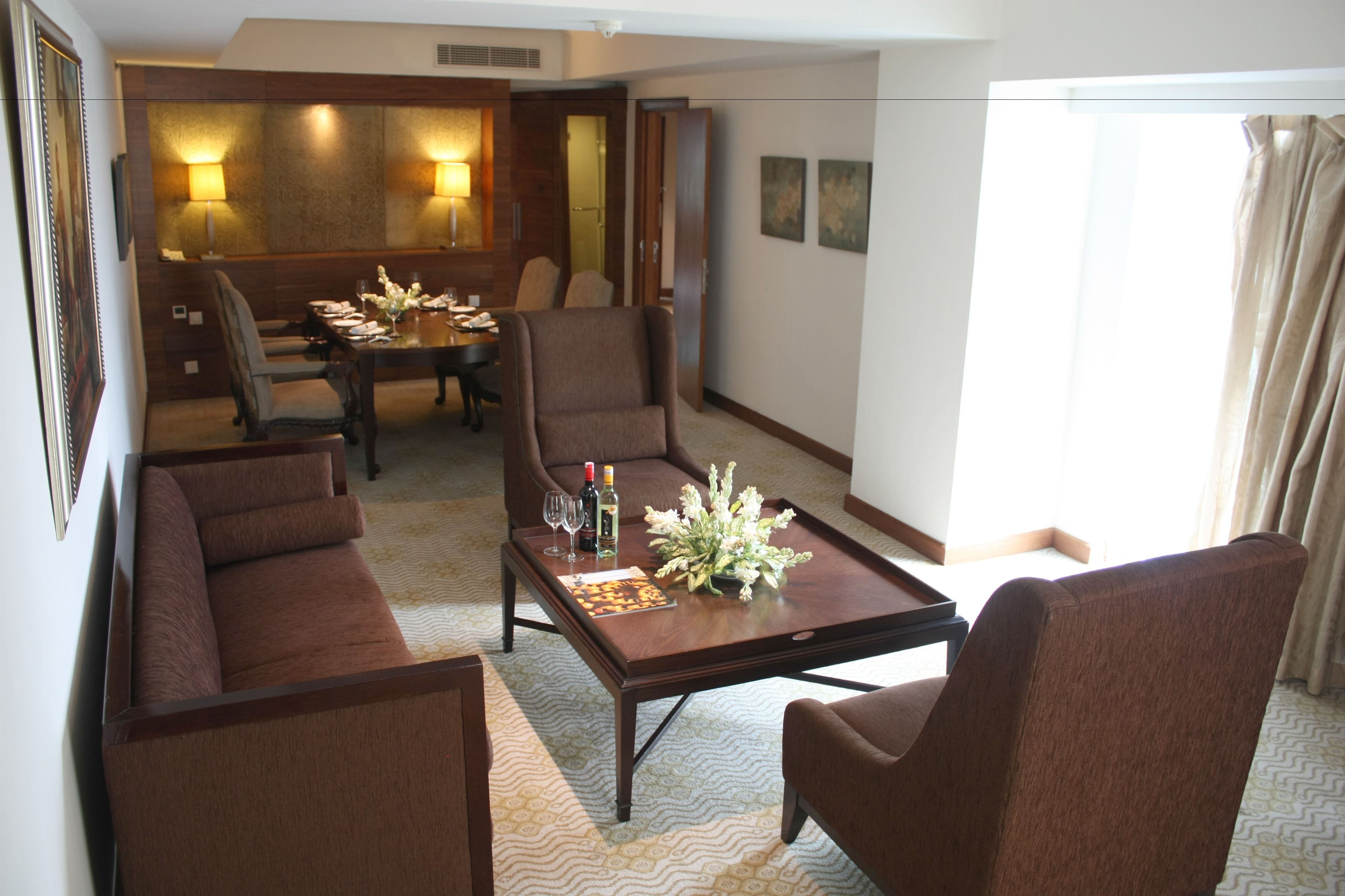 Une chambre d’hôtel comprenant un coin repas, un ensemble de canapés et une table basse agrémentée d’un arrangement floral.