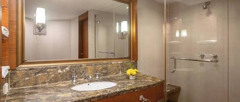 A bathroom with a marble sink, a large mirror, a glass shower enclosure, and a towel rack.