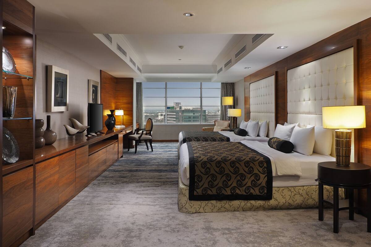 A hotel room with a large bed, a desk, a chair, and a view of the city.