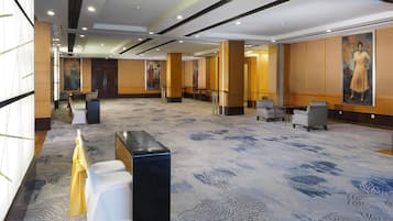 A spacious lobby with a patterned carpet, seating areas, and artwork on the walls.