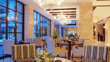 A spacious lobby with large windows, modern chandeliers, and comfortable seating areas.