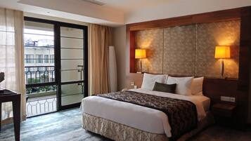 A hotel room with a large bed, two bedside lamps, a view of the outside balcony, and a patterned headboard.