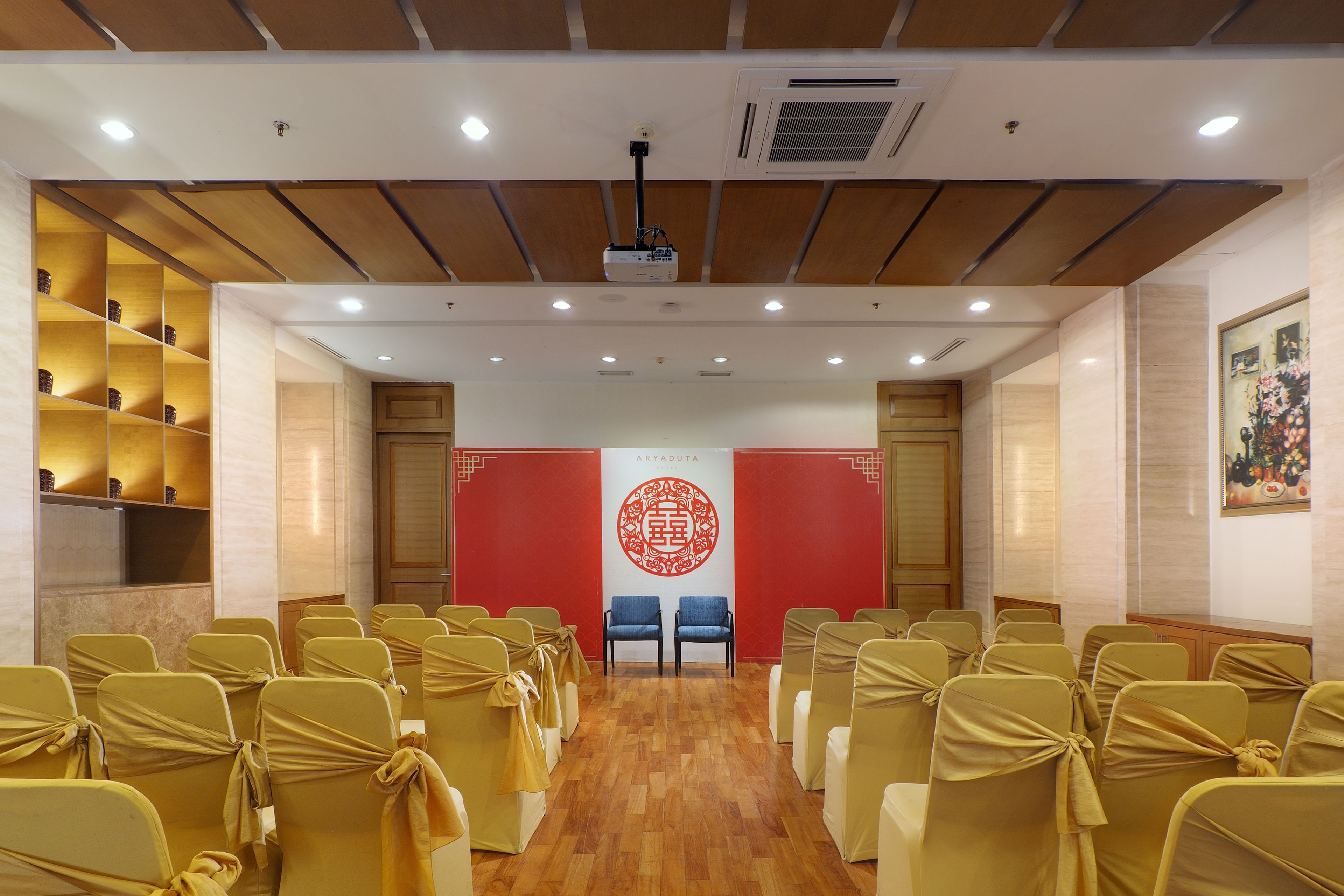 A conference room with rows of chairs, a podium, and a red banner with a logo.