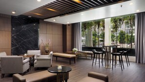 A modern lounge area with leather sofas, a coffee table, and bar stools. - Aryaduta Medan (Medan)