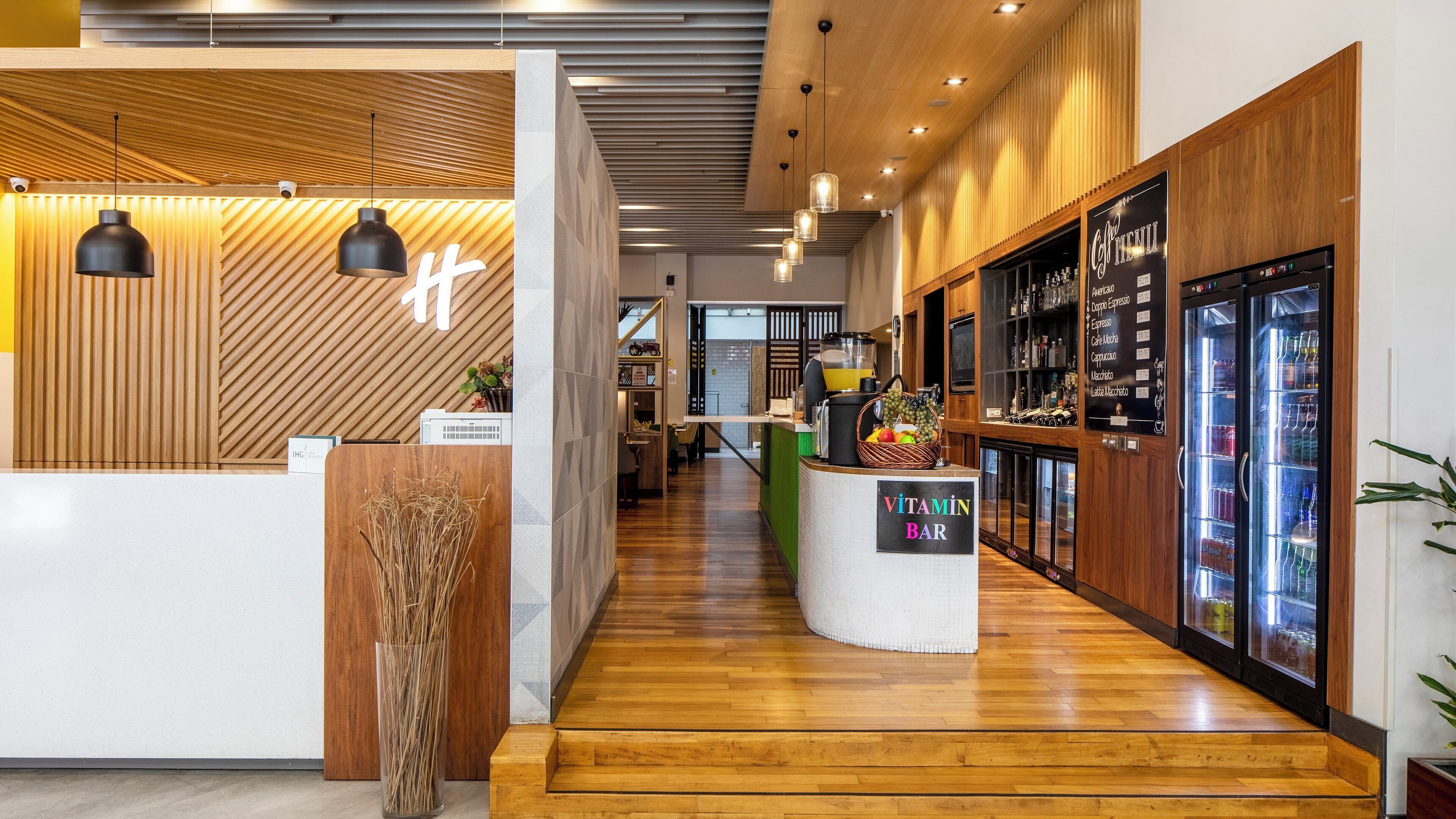 Un bar moderno con detalles de madera y una pantalla mostrando el menú.