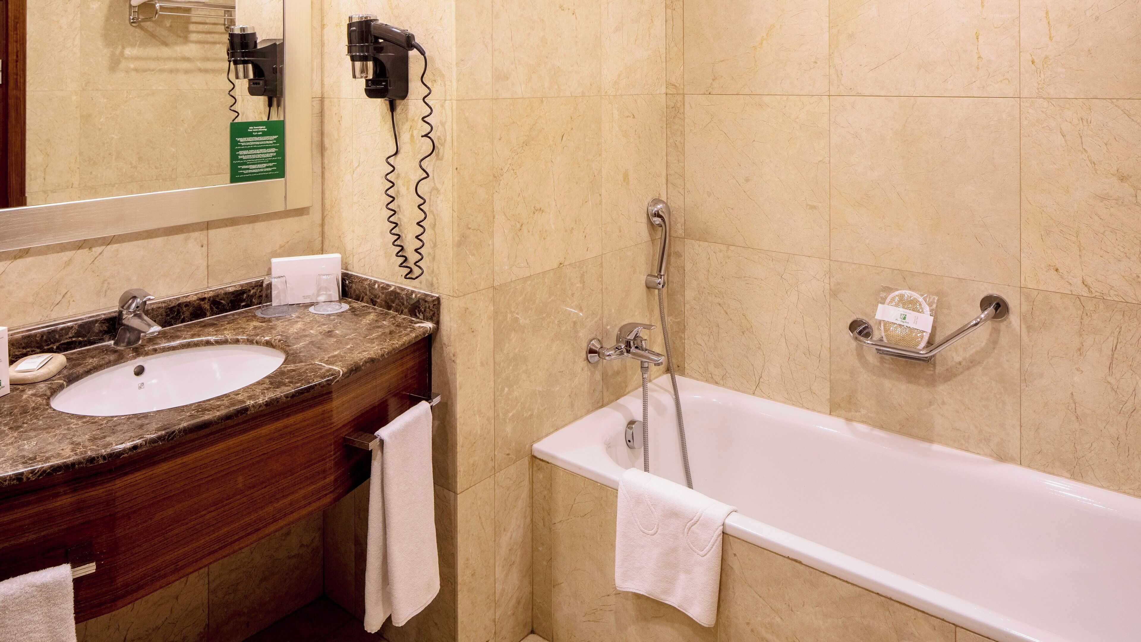 A bathroom with a marble sink, a mirror, a towel rack, and a bathtub.