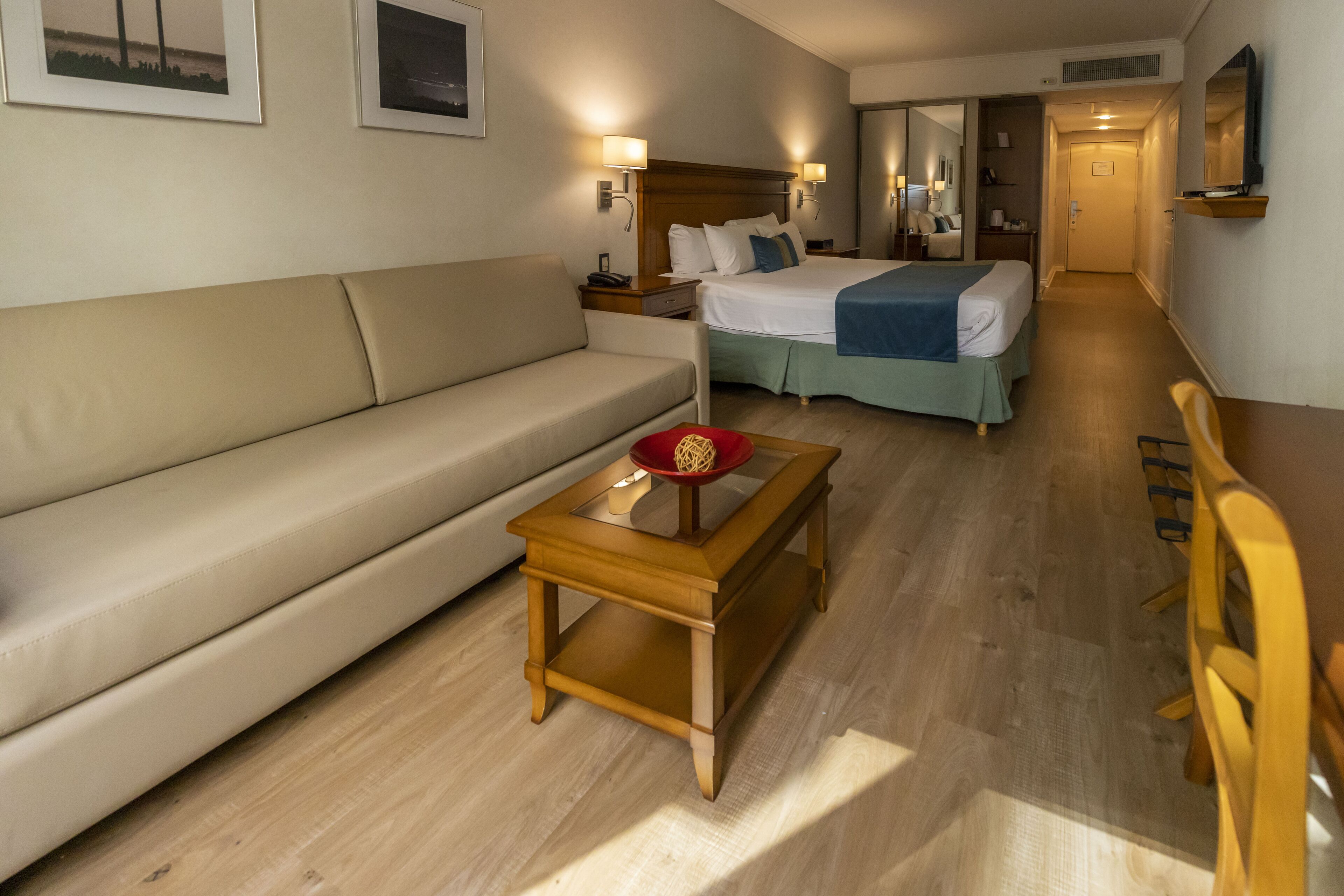 A hotel room with a bed, a sofa, a small table, and a chair.