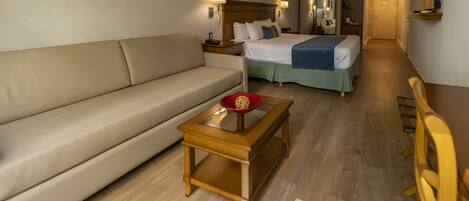 A hotel room with a bed, a sofa, a small table, and a chair.