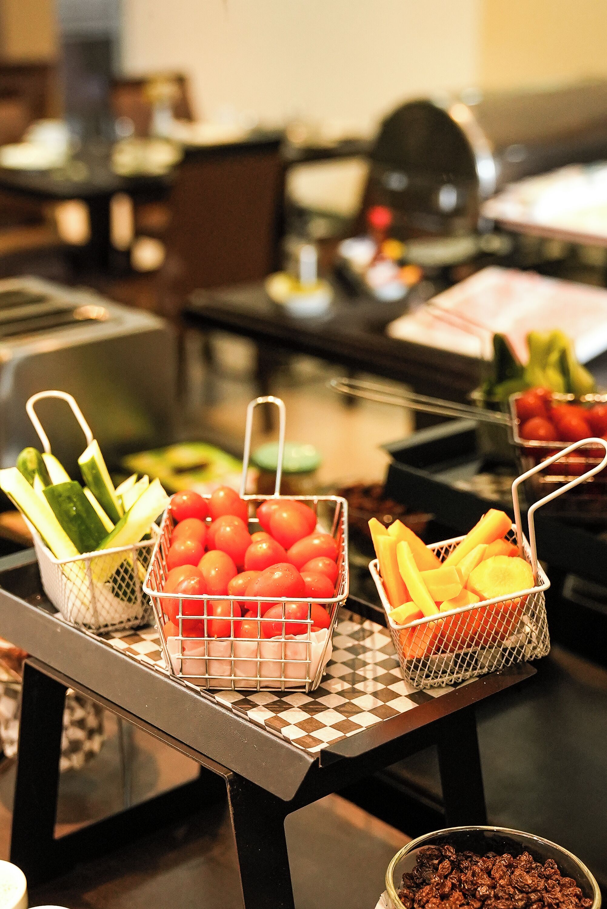 Une table de buffet proposant divers aliments, notamment des tomates, des concombres et des carottes.